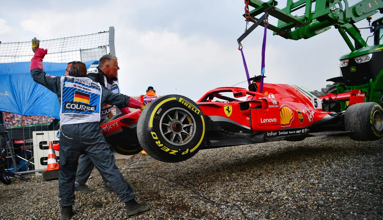 Petugas mengangkat mobil pebalap Jerman, Sebastian Vettel menggunakan traktor saat balapan F1 Grand Prix di Hockenheim racing circuit, Jerman, (22/7/2018). Vettel kehilangan kendali saat perubahan cuaca dan menabrak pembatas. (AFP/Andrej Isakovic)