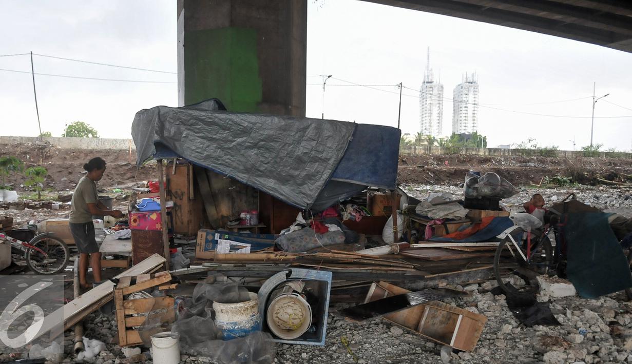 Penghuni kolong Tol memasang terpal di tempat tinggalnya sementara usai ditertibkan oleh Pemprov DKI, Jakarta, (16/9). Sebelumnya, 50 bangunan liar di bawah kolong Tol Sedyatmo, Penjaringan kembali ditertibkan Pemkot Jakut. (Liputan6.com/Yoppy Renato)