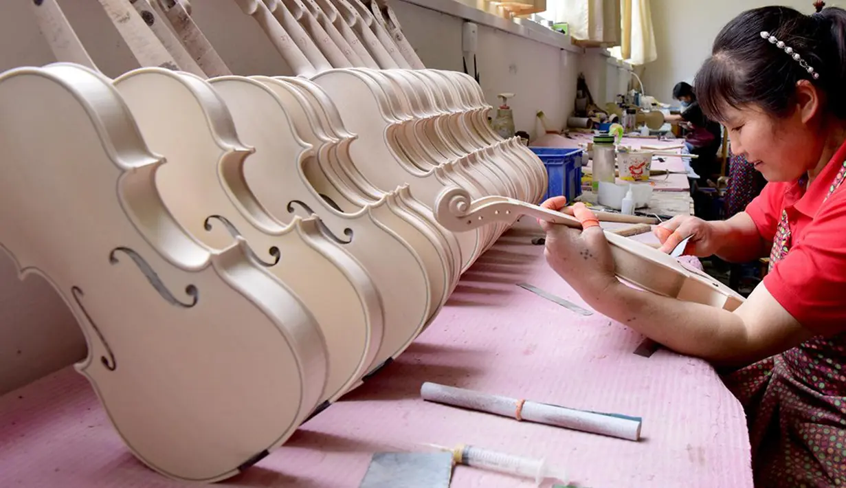 Para pekerja membuat biola di sebuah bengkel kerja di Queshan, Provinsi Henan, China, Rabu (20/5/2020). Kawasan industri penghasil alat musik tersebut mampu memproduksi 30.000 biola dan selo setiap tahun. (Xinhua/Zhu Xiang)