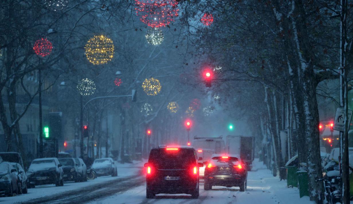 Philippe Tabarot juga mengimbau masyarakat untuk melakukan perjalanan sesedikit mungkin di jalan raya dan bekerja dari rumah. Tampak dalam foto, mobil-mobil melaju saat salju menyelimuti jalanan di Paris pada 7 Januari 2026. (Ludovic MARIN/AFP)