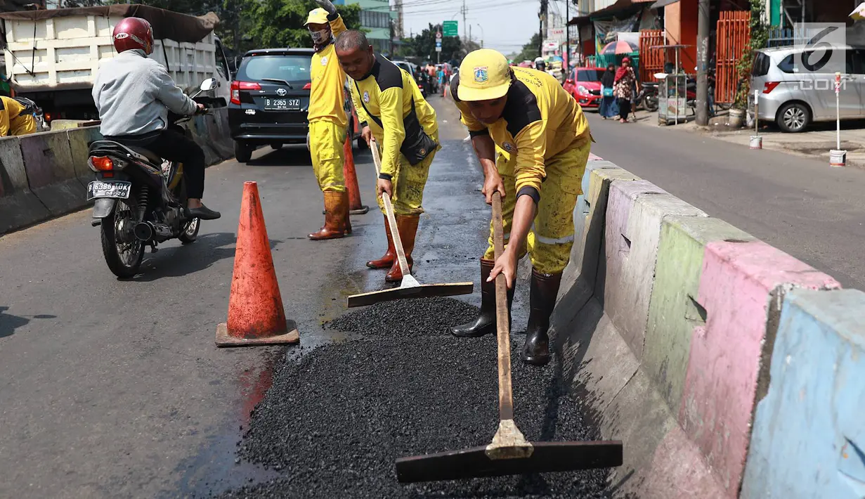 Petugas Bina Marga Pasar Minggu menambal jalan yang rusak di Jalan Raya Ragunan, Jakarta, Senin (22/4). Petugas mengaku bahwa keberadaan beton pembatas jalan justru membuat jalan di kawasan tersebut selalu rusak setiap hujan deras karena menimbulkan genangan air. (Liputan6.com/Immanuel Antonius)
