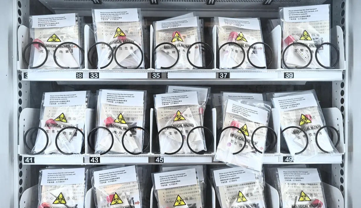 Alat test kit COVID-19 ditampilkan pada mesin penjual otomatis (vending machine) di stasiun kereta bawah tanah MTR di Hong Kong pada Senin (7/12/2020).  Mesin penjual otomatis tersebut akan memasok 10.000 alat tes COVID-19 dalam sehari. (Anthony WALLACE / AFP)