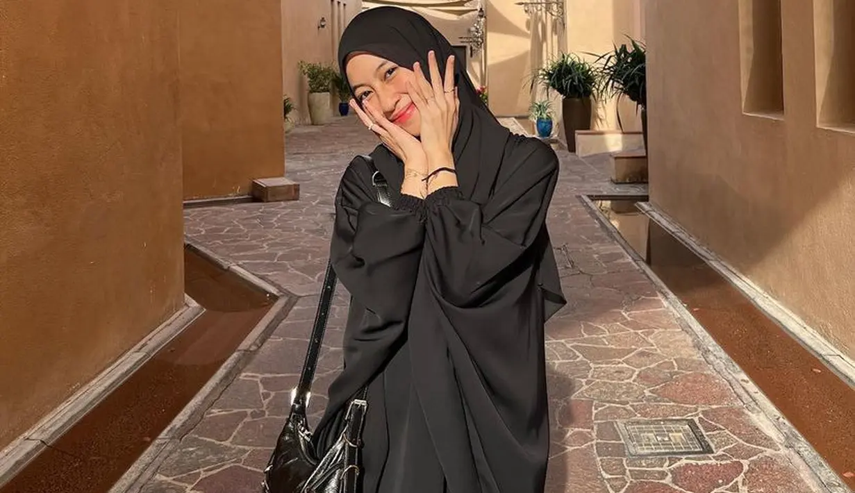 Adiba mengenakan dress hitam loose yang serasi dengan kerudung panjangnya. Serasi dengan mini shoulder bagnya.  [@adiba.knza]