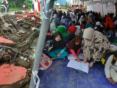 Murid-murid korban gempa belajar pada tenda darurat yang dibangun di halaman sekolah di SDN Gintung, Mangunkerta, Cianjur, Jumat (23/12/2022). Lebih dari sebulan sejak musibah gempa bumi 5,2 SR sejumlah murid sekolah di Cianjur masih belajar pada tenda darurat. (merdeka.com/Arie Basuki)