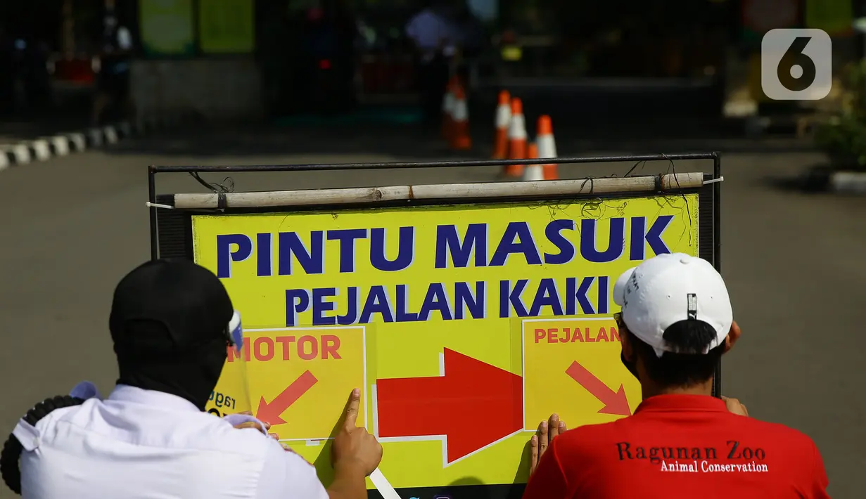 Petugas memasang penunjuk akses masuk pengunjung di Taman Margasatwa Ragunan, Jakarta, Sabtu (20/6/2020). Ragunan mulai dibuka kembali untuk pengunjung pada Sabtu ini di masa PSBB transisi dengan pembatasan dan penerapan protokol kesehatan yang ketat. (Liputan6.com/Herman Zakharia)