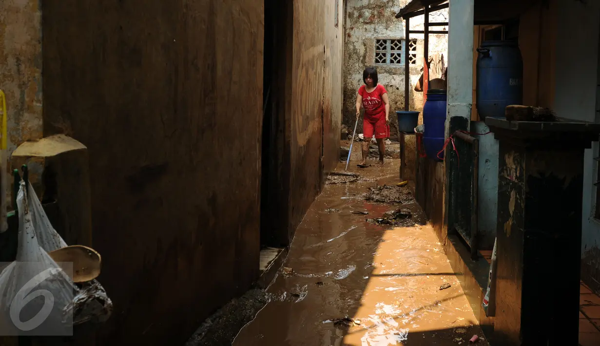 Warga membersihkan sisa lumpur di gang sekitar rumahnya di Rawajati, Kalibata, Jakarta, Senin (16/11/2015). Hujan deras yang melanda Bogor, Minggu (15/11) mengakibatkan puluhan rumah di bantaran sungai Ciliwung terendam. (Liputan6.com/Helmi Fithriansyah)