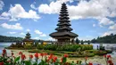 Ketenangan air Danau Beratan menciptakan refleksi yang indah dari pura dan pegunungan di permukaannya. Tampak dalam foto, sejumlah pemuda bersiap mengikuti prosesi keagamaan di Pura Ulun Danu Beratan, sebuah pura Hindu di Danau Beratan dekat Bedugul, Bali, pada Jumat 7 November 2025. (Mladen ANTONOV/AFP)