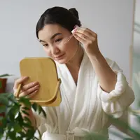 ilustrasi perempuan mengaplikasikan skincare di wajah/copyright freepik.com/freepik