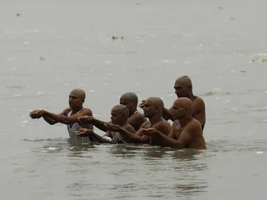 Penjual susu (kanan) menyaksikan umat Hindu melakukan ritual selama gerhana matahari di pertemuan Sungai Gangga dan Sungai Yamuna di Sangam, Prayagraj, India, Minggu (21/6/2020). Fenomena gerhana matahari pada 21 Juni 2020 terlihat dari berbagai negara di dunia. (AP Photo/Rajesh Kumar Singh)