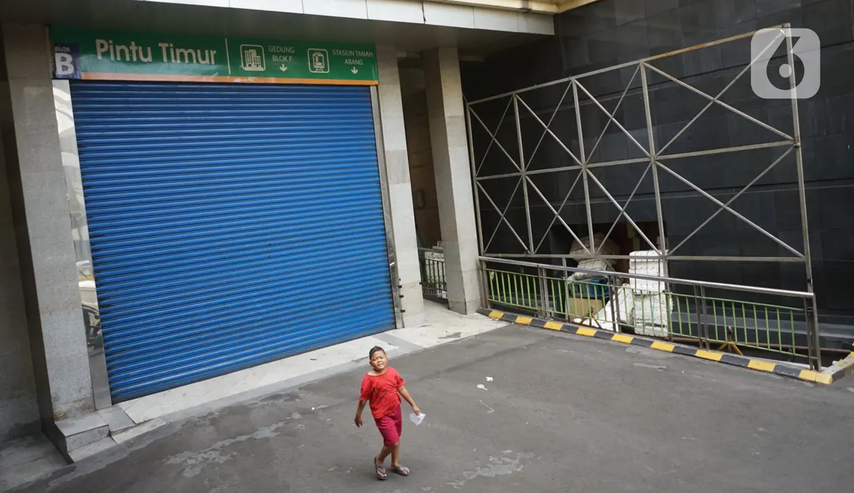 Seorang anak berjalan melewati pertokoan yang tutup di Pasar Tanah Abang, Jakarta, Senin (11/5/2020). Pemerintah Provinsi DKI Jakarta kembali memperpanjang penutupan sementara Pasar Tanah Abang hingga 22 Mei 2020 untuk mencegah penyebaran virus corona COVID-19. (Liputan6.com/Immanuel Antonius)