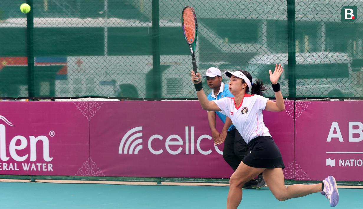 Petenis putri Indonesia, Aldila Sutjiadi berusaha mengembalikan bola ke arah petenis Thailand, Aunchisa Chanta pada pertandingan final tenis beregu putri SEA Games 2023 di Tennis Arena, Morodoc Techo National Stadium, Phnom Penh, Kamboja, Selasa (9/5/2023). Indonesia sempat tertinggal di partai pertama namun sukses menyamakan kedudukan saat partai kedua. Pasangan Aldila dan Jessy kemudian sukses menyegel kemenangan partai ketiga sekaligus memberikan emas ke-24 untuk Indonesia. (Bola.com/Abdul Aziz)