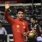 Pembalap Ferrari Charles Leclerc melambaikan tangan kepada penonton setelah meraih posisi terdepan dalam sesi kualifikasi jelang balapan Formula 1 atau F1 GP Singapura di Sirkuit Marina Bay Sirkuit Marina Bay Street, Sabtu (2/10/2022) malam WIB. (Lillian SUWANRUMPHA / AFP)