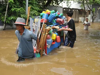 Warga membantu mendorong gerobak penjual prabotan di komplek Polri jalan Pondok Karya, Mampang, Jakarta, Kamis (21/4). Banjir setinggi 120cm disebabkan meluapnya Kali Mampang. (Liputan6.com/Gempur M Surya)