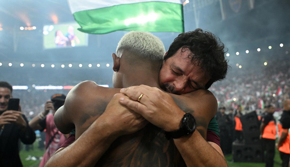 Pemain Fluminense, John Kennedy berpelukan dengan pelatih Fernando Diniz saat merayakan kemenangan atas Boca Juniors pada final Copa Libertadores yang berlangsung di Maracana Stadium , Rio de Janeiro, Brasil, 5 November 2023 WIB. (AFP/Carl De Souza)