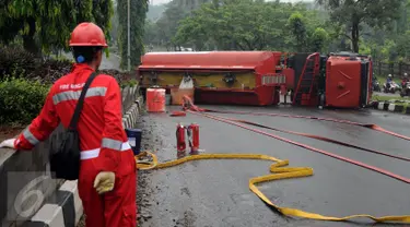 Petugas pemadam api dari Pertamina melihat kondisi truk tangki BBM yang terbalik di ruas Jalan Tegar Beriman Kabupaten Bogor, Jumat (15/4/2016). Menurut warga, truk tangki terbalik sekitar pukul 05.00 dini hari. (Liputan6.com/Helmi Fithriansyah)