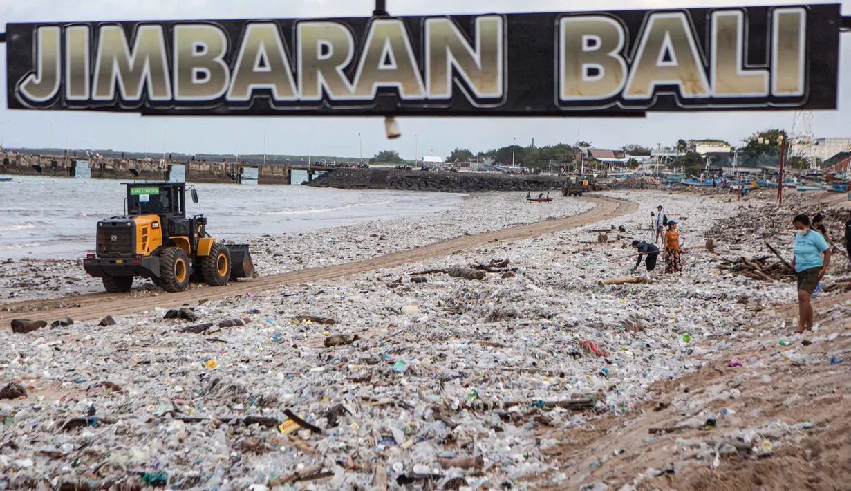 Tumpukan sampah ini menjadi keluhan wisatawan sekaligus memberikan tekanan ekonomi bagi pelaku usaha restoran di sepanjang garis pantai. Tampak dalam foto, para pekerja dan warga membersihkan ceceran dan tumpukan sampah plastik yang terdampar di Pantai Jimbaran, Bali, pada Selasa 10 Maret 2026. (Lana Priatna/AFP)