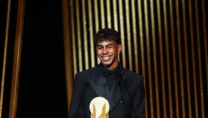 Penyerang muda Barcelona, Lamine Yamal, menerima Kopa Trophy, lambang pemenang predikat pemain muda terbaik di seremonial Ballon d'Or yang berlangsung di Theatre du Chatelet di Paris, Senin (28/10/2024) malam waktu setempat. (FRANCK FIFE / AFP)