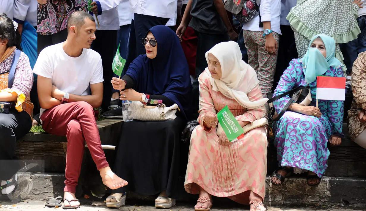 Warga duduk di trotoar jalan untuk menyambut kedatangan Raja Salman bin Abdulaziz di sekitar Istana Bogor, Rabu (1/3). 21 dentuman meriam dan kibaran bendera kedua negara mewarnai sambut Raja Salman. (Liputan6.com/Helmi Fithriansyah)