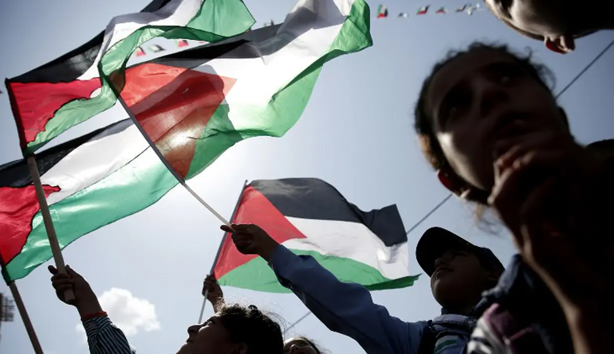 Warga Palestina melambaikan bendera nasional mereka saat menunggu live-screening pidato Presiden Mahmud Abbas sebelum pengibaran bendera Palestina di markas besar PPB di New York, Rabu (30/9/2015). (AFP PHOTO/ABBAS Momani)