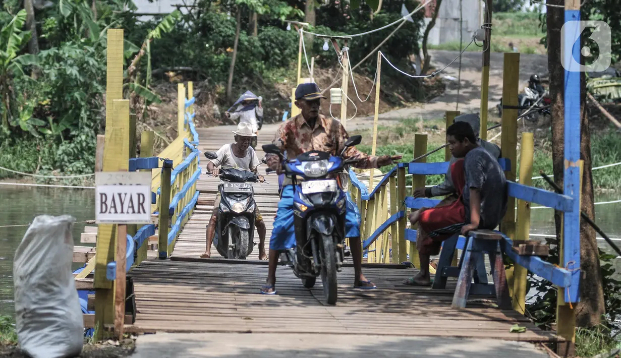 Warga memberikan uang kepada penjaga usai melintasi jembatan apung di Desa Sukamekar, Kecamatan Sukawangi, Kabupaten Bekasi, Jawa Barat, Kamis (17/2/2022). Warga mengaku adanya  jembatan tersebut sangat membantu dalam beraktivitas karena tidak harus memutar jalan. (merdeka.com/Iqbal S. Nugroho)