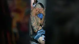 Seorang pria bereaksi saat tubuhnya ditato dalam dalam acara Tattoo Week tahunan di Rio de Janeiro, Brasil (12/1). Ajang perhelatan seniman dan penggemar tato ini diadakan setiap tahunnya di Brasil. (AFP Photo/Mauro Pimentel)