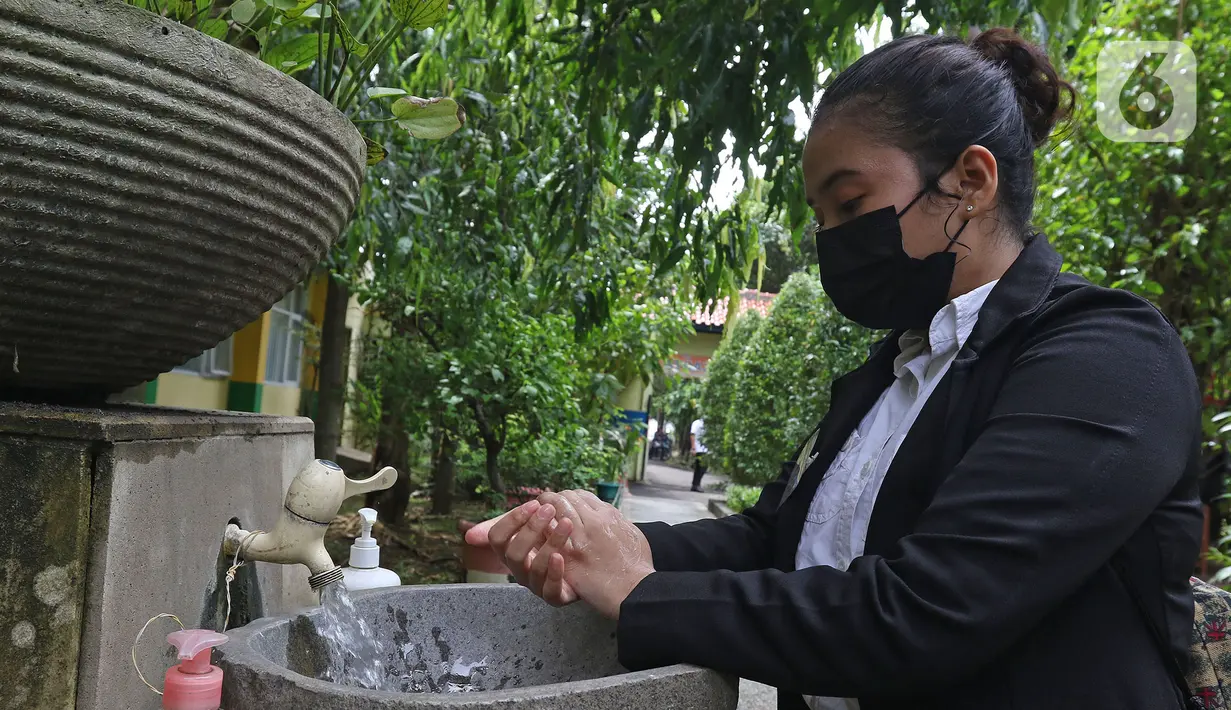 Murid sedang mencuci tangan saat tiba di sekolah  SMKN 51, Jakarta, Rabu (7/4/2021). Para murid diwajibakan membawa makanan sendiri  dan mengikuti syarat & panduan sekolah tatap muka seperti membuka pintu dan jendela.(Liputan6.com/Herman Zakharia)