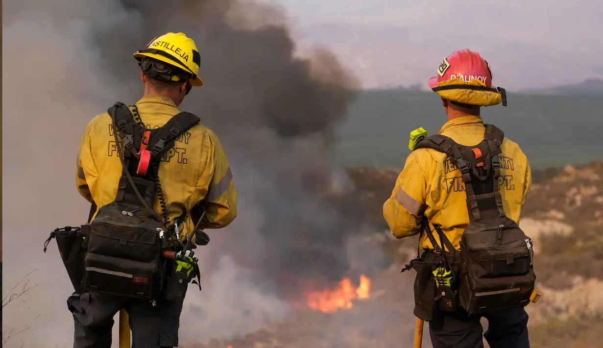 Petugas pemadam kebakaran menyaksikan api membakar di lereng bukit Selasa (6/9/2022), dekat Hemet, California. Pada Selasa malam api telah membakar 4.500 hektar dan 5% terkandung, menurut tweet dari Cal Fire. (AP Photo/Ringo H.W. Chiu)