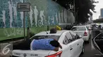 Seorang sopir tidur diatas bagasi taksi saat demo di depan Gedung DPR/MPR, Jakarta, Selasa (22/3). Selain melakukan demo, sopir taksi tersebut melakukan sweeping ke supir taksi yang beroperasi di dalam tol, dan membakar ban. (Liputan6.com/Johan Tallo)