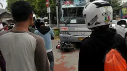 Sejumlah warga menyaksikan evakuasi sepeda motor yang tertabrak Bus Transjakarta di kawasan permata hijau, Jakarta, Jumat (27/3/2015). Sejumlah warga sedang melakukan evakuasi speda motor yang berada di dalam bus transjakarta. (Liputan6.com/Johan Tallo)