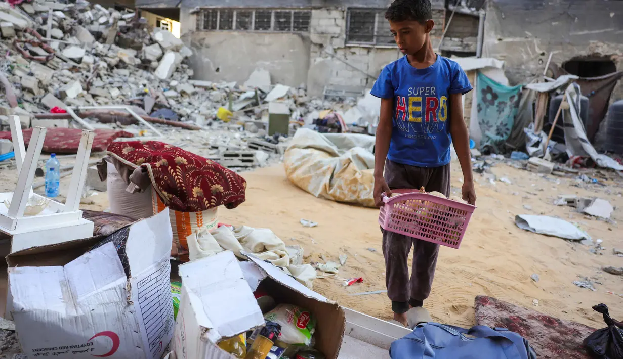 Seorang anak laki-laki menyelamatkan barang-barang dari reruntuhan rumahnya yang hancur akibat serangan Israel di Khan Younis, Jalur Gaza selatan, pada Rabu 29 Oktober 2025. Badan pertahanan sipil Gaza mengatakan pada Rabu 29 Oktober 2025 bahwa puluhan serangan Israel menghantam sejumlah wilayah. (BASHAR TALEB/AFP)