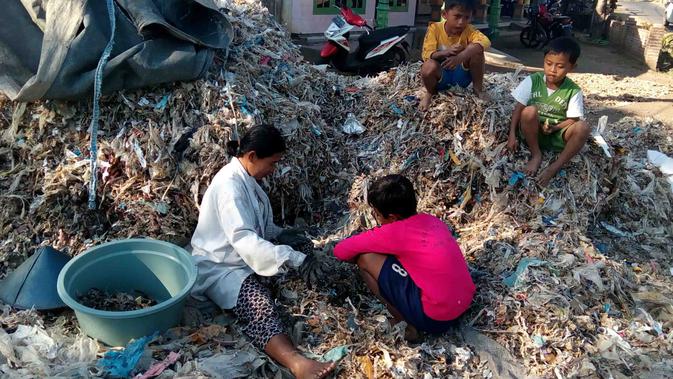 Tiamah ditemani sejumlah bocah di Desa Gampingan, Pagak, Malang, memilah sampah impor yang dibeli dari sebuah perusahaan kertas (Liputan6.com/Zainul Arifin)