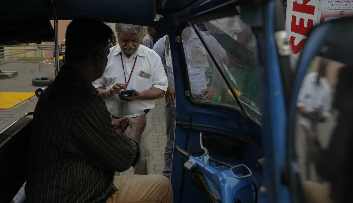 Seorang pekerja memindai kode QR sebelum mengisi bensin ke kendaraan di sebuah pompa bensin di Kolombo, Sri Lanka, Senin, 1 Agustus 2022. Sri Lanka memperkenalkan distribusi bahan bakar menggunakan kode QR pada hari Senin sebagai bagian dari penerapan kuota mingguan untuk pengendara. (AP Photo/Eranga Jayawardena)