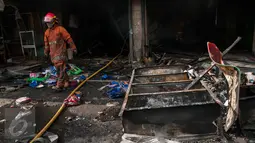 Petugas Damkar melintas di dekat bangunan yang terbakar di Pasar Senen, Jakarta, Kamis (19/1). Penyebab kebakaran masih dalam tahap penyelidikan. (Liputan6.com/Gempur M Surya)