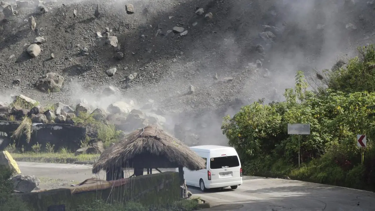 Batu-batu besar berjatuhan saat kendaraan melewati jalan selama gempa bumi di Bauko, Filipina pada Rabu 27 Juli 2022. (AP Photo/Harley Palangchao)
