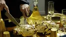 Seniman Prancis, Frederique Lecerf membungkus ayam dengan lembaran emas tipis 24 karat dalam acara makan malam di Paris, 28 Maret 2019. Tidak hanya makanan, balutan warna emas menyelimuti peralatan makan di atas meja. (REUTERS/Philippe Wojazer)