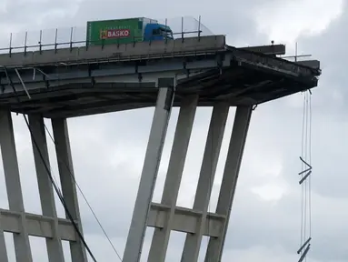Sebuah truk berada di atas jembatan Morandi, dekat dengan bagian jalan layang yang runtuh, di Genoa, italia, Rabu (14/8). Insiden ambrolnya jembatan itu menyebabkan35 orang tewas dan mobil-mobil jatuh dari ketinggian sekitar 200 meter. (AFP/Valery HACHE)