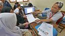Petugas memberikan formulir pendaftaran seleksi Penerimaan Peserta Didik Baru (PPDB) di SMAN 1 Depok,  Kota Depok, Jawa Barat, Selasa (18/6/2019). Sistem PPDB Jawa Barat berlangsung pada tanggal 17-22 Juni 2019. (Liputan6.com/Herman Zakharia)