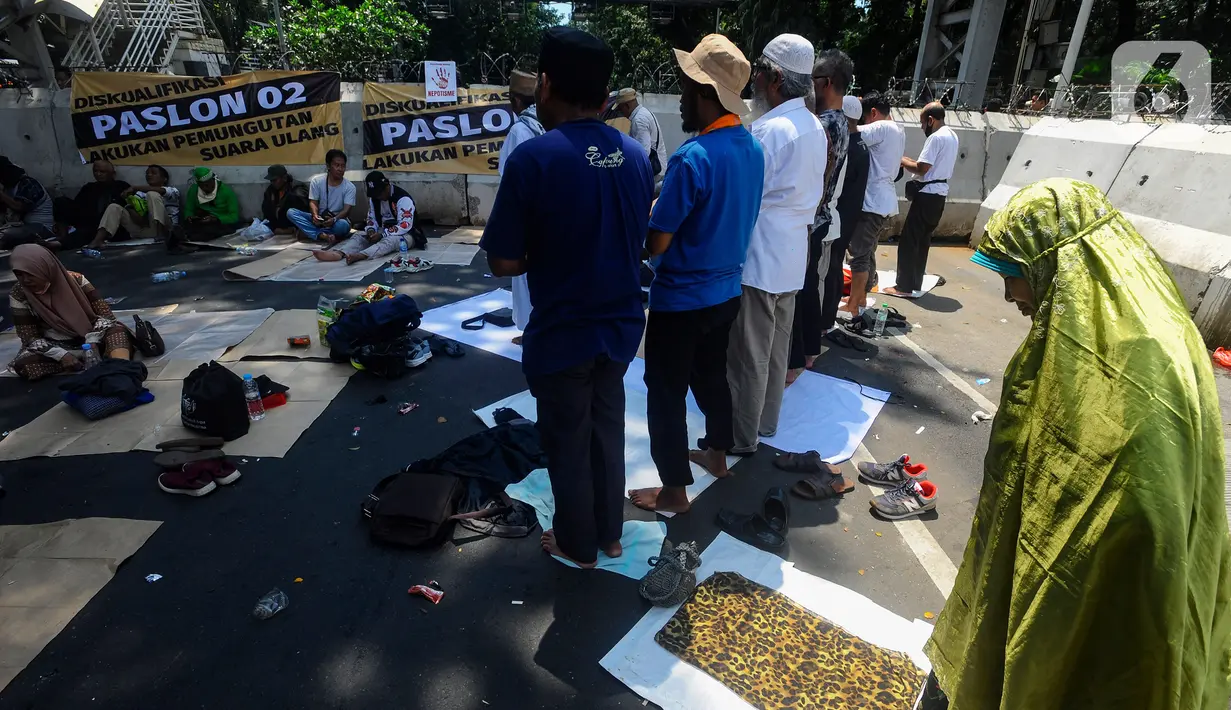 Massa demo menggelar salat zuhur dengan beralaskan terpal hingga sajadah yang dibawa masing-masing. (merdeka.com/Arie Basuki)