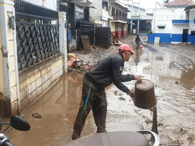Warga membersihkan lumpur sisa dari banjir bandang Garut di kawasan Cimacan, Desa Jayaraga, Kecamatan Tarogong Kidul, Sabtu (16/7/2022). Pemda Garut, Jawa Barat menyatakan status darurat banjir setelah 8 kecamatan di wilayah tersebut terendam banjir usai Sungai Cimanuk dan beberapa anak sungainya meluap. (Liputan6.com/Jayadi Supriadin)