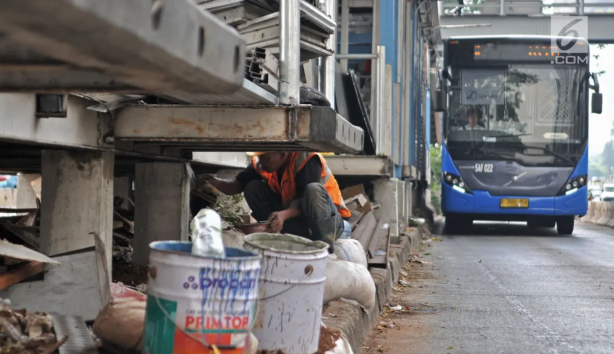 Bus Transjakarta melintas saat pekerja mengerjakan proyek perluasan Halte Bus Transjakarta Gelora Bung Karno (GBK) di Jalan Jenderal Sudirman, Jakarta, Selasa (24/7). (Liputan6.com/Faizal Fanani)