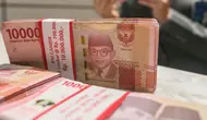 Teller menunjukan mata uang rupiah di Jakarta, Senin (26/2/2024). (Liputan6.com/Angga Yuniar)