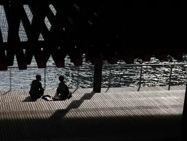 Pasangan berbincang saat menikmati musim semi yang hangat di tepi air di Manhattan di New York City (8/4). Sebagian besar Pantai Timur mengharapkan suhu hangat terus sepanjang minggu. (Spencer Platt/Getty Images/AFP)