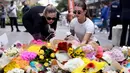 Orang-orang meletakkan bunga di luar pusat perbelanjaan Westfield Bondi Junction di Sydney pada 14 April 2024. (DAVID GRAY/AFP)