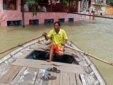 Warga menggunakan perahu sebagai sarana transportasi saat banjir bandang melanda wilayah Allahabad, India (26/8). (REUTERS/Jitendra Prakash)