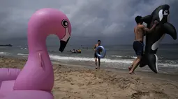 Seorang pria bermain dengan ban karet lumba-lumba di pantai Sijung Ho di Korea Utara (14/7/2019). Pantai Sijung Ho merupakan tujuan wisata populer bagi penduduk lokal dan asing. (AP Photo/Vincent Yu)