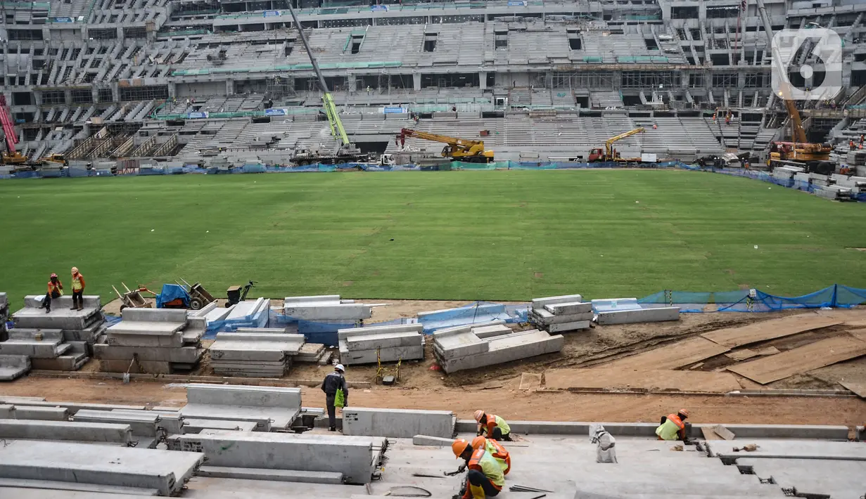 Aktivitas pekerja di dekat lapangan utama lapangan utama Jakarta International Stadium (JIS), Selasa (26/10/2021). Rumput rekomendasi FIFA ini digadang-gadang mampu digunakan mencapai 1.000 jam pertandingan dalam setahun dan memiliki daya serap air yang baik. (merdeka.com/Iqbal S Nugroho)