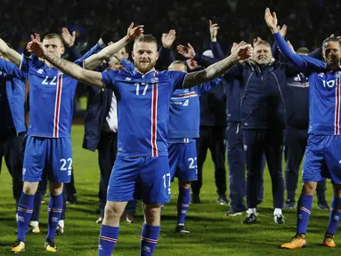 Kapten Islandia, Aron Gunnarsson, bersama rekan-rekannya merayakan keberhasilan lolos ke Piala Dunia 2018 usai mengalahkan Kosovo di Reykjavik, Senin (9/10/2017). Islandia untuk pertama kali dalam sejarah lolos ke Piala Dunia. (AP/Brynjar Gunnarsson)
