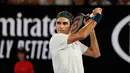 Petenis Swiss, Roger Federer mengembalikan bola ke arah Taylor Fritz dari AS dalam babak 32 besar Australia Terbuka di Melbourne, Jumat (18/1). Federer melaju mulus ke babak 16 besar setelah menang tiga set langsung 6-2 7-5 6-2. (DAVID GRAY/AFP)