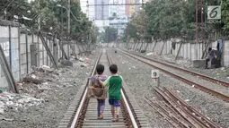 Dua anak berjalan usai bermain di sekitar rel kereta api di kawasan Pademangan, Jakarta, Kamis (8/11). Kurangnya lahan bermain menyebabkan anak-anak tersebut bermain di tempat yang tidak semestinya dan membahayakan. (Liputan6.com/Immanuel Antonius)