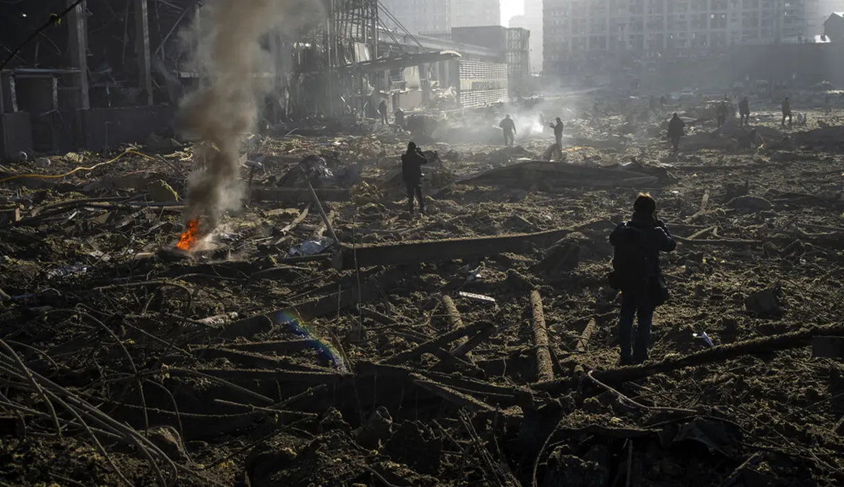 Orang-orang berkumpul di tengah kehancuran setelah serangan sebuah pusat perbelanjaan di Kiev, Ukraina, Senin (21/3/2022). Delapan orang tewas dalam serangan tersebut. (AP Photo/Rodrigo Abd)